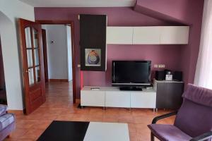 sala de estar con paredes de color púrpura y TV en Casa céntrica en Platja d'Aro, a 5min de la playa, en Platja d'Aro