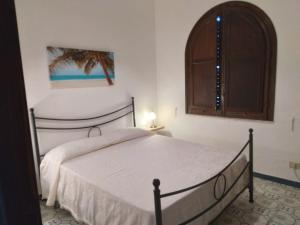 a bedroom with a white bed with a wooden cabinet at Villa magaggiari 2 in Cinisi