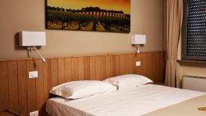 ein Schlafzimmer mit einem Bett mit zwei Lampen an der Wand in der Unterkunft Eco Rooms & Apartments in Voghera