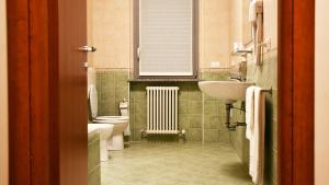 baño con lavabo y aseo y ventana en Eco Rooms & Apartments, en Voghera