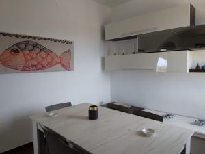 a kitchen with a table with a fish picture on the wall at Villa magaggiari 2 in Cinisi