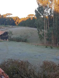 un grand champ herbeux avec une maison et des arbres dans l'établissement CHÁCARA QUEDINHA D'ÁGUA, à Campo Alegre