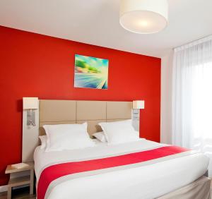 - une chambre avec un mur rouge et un lit dans l'établissement Séjours & Affaires Paris Bagneux, à Bagneux