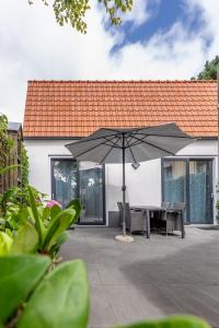 a patio with a table and an umbrella at Vakantiehuis Rehoboth in Domburg