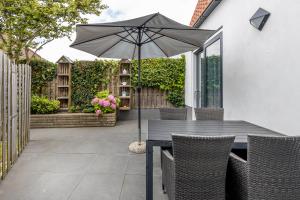 a wooden table with an umbrella on a patio at Vakantiehuis Rehoboth in Domburg