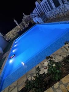 una piscina iluminada de azul por la noche en فيلا الغروب الجبل الأخضر, en Ḩayl Yaman