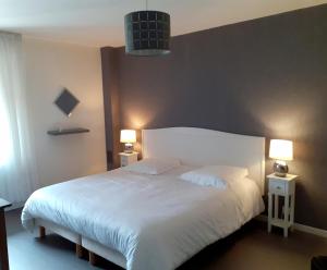 1 dormitorio con 1 cama blanca grande y 2 lámparas en BONSEJOUR, en Saint-Maurice-sur-Moselle