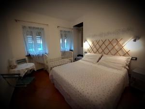 a bedroom with a white bed and two windows at B&B I Glicini in Vescina