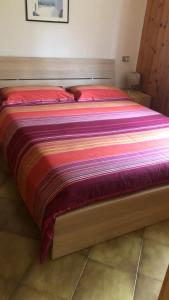 a large bed with a colorful blanket on it at Rododendro Apartment in Passo San Pellegrino