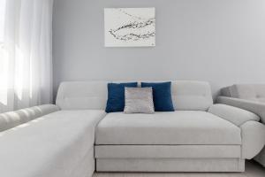a white living room with a couch with blue pillows at Przymorze Apartment Jagiellońska by Renters in Gdańsk