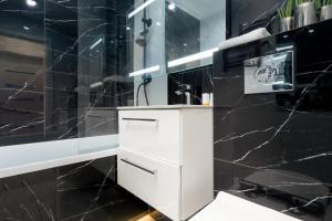 a black and white bathroom with a sink and a shower at Przymorze Apartment Jagiellońska by Renters in Gdańsk