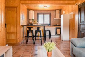 cocina y sala de estar con mesa y nevera en Aldea Los Odres - Cabañas de Madera de 1ª con Piscina Privada y BBQ en la puerta, en Moratalla