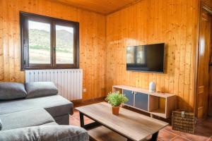 Una sala de estar con un sofá y un televisor. en Aldea Los Odres - Cabañas de Madera de 1ª con Piscina Privada y BBQ en la puerta, en Moratalla