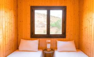 Dos camas en una habitación con ventana. en Aldea Los Odres - Cabañas de Madera de 1ª con Piscina Privada y BBQ en la puerta, en Moratalla