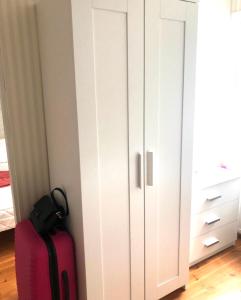 ein weißer Schrank mit einem rosa Koffer daneben. in der Unterkunft Villa Alex in Helsinki