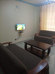 ein Wohnzimmer mit einem Sofa, einem Tisch und einem TV in der Unterkunft Legend Executive Suites in Fort Portal