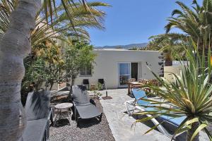a patio with chairs and a house with palm trees at Bungalow Moijama el Drago in Los Llanos de Aridane