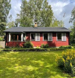 una casa roja con un patio verde delante de ella en Fyrvägen 13 'Ydermossa' NEW!, en Munka-Ljungby