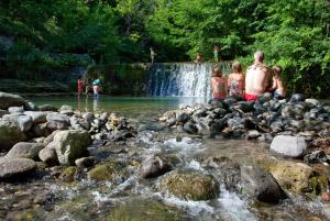 Eine Gruppe von Menschen, die auf Felsen in einem Fluss sitzen in der Unterkunft Ludocamping in Lussas