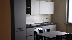 a kitchen with white cabinets and a table and a sink at Eco Rooms & Apartments in Voghera