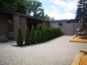 a patio with a fence and some bushes and trees at Poilsio namelis in Palanga