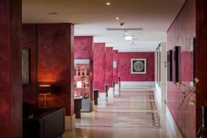 a hallway with red walls and a long hallway with tables at Vila Gale Cascais in Cascais