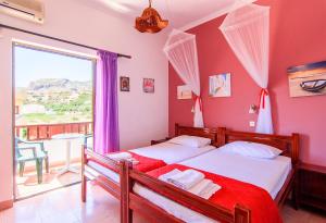 a bedroom with two beds and a large window at Savas Rooms in Palaiochora