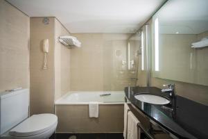 a bathroom with a tub and a toilet and a sink at Vila Gale Cascais in Cascais