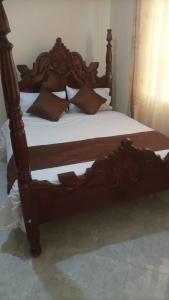 a bed with a wooden frame with pillows on it at Legend Executive Suites in Fort Portal