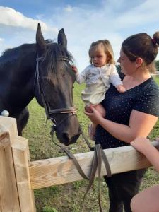 una mujer sosteniendo un bebé de pie junto a un caballo en B&B DeSo, en Zonnebeke