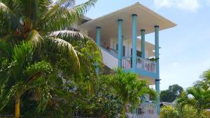 a white house with blue columns and palm trees at La Villa Therese in Anse Royale