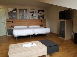 sypialnia z dwoma łóżkami, stołem i telewizorem w obiekcie Apartamentos Turísticos y Habitaciones Cidade Vella by Bossh! Hotels w mieście Ourense