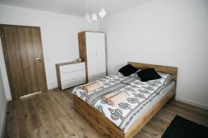 1 dormitorio con cama de madera y almohadas en Apartamenty Perła Orawy, en Zubrzyca Dolna