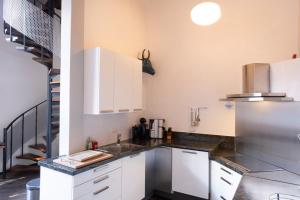uma cozinha com armários brancos e um lavatório em Meschermolen 14 em Mesch
