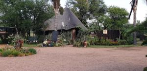 une maison avec un toit de chaume dans un jardin dans l'établissement Grootgeluk, à Naboomspruit