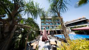 a pool with chairs and umbrellas next to a hotel at Laren Family Hotel & Spa - Boutique Class in Antalya