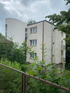 Biały budynek z płotem przed nim w obiekcie Apartament nad Kryniczanką w mieście Krynica Zdrój