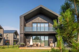 a house with a balcony with a table and a umbrella at Vila „Neptūnas“ in Palanga
