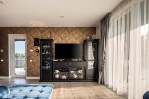 a living room with a tv and a blue couch at Vila „Neptūnas“ in Palanga
