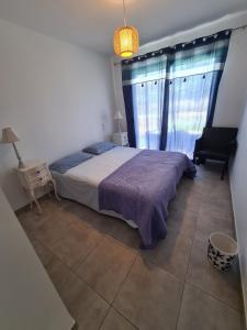 um quarto com uma cama, uma cadeira e uma janela em Petite maison - annexe indépendante d'une villa / Independent Guesthouse within a villa em Corneilla-del-Vercol