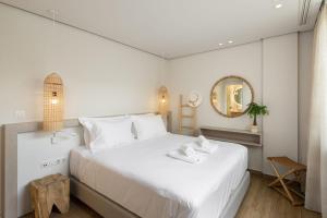 a white bedroom with a large white bed and a mirror at Luria Homes in Lagomandra