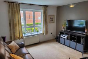 a living room with a couch and a flat screen tv at Stylish 2 bed 2 bathroom apartment for up to 5 in Warwick