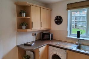 cocina con lavadora, fregadero y microondas en Stylish 2 bed 2 bathroom apartment for up to 5 en Warwick