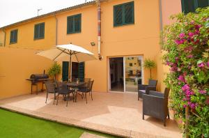 a patio with a table and chairs and an umbrella at Casa Robes Sa Pobla 170 by Mallorca Charme in Sa Pobla