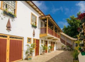 a large white building with red doors and a garage at Pouso do Manu in Tiradentes