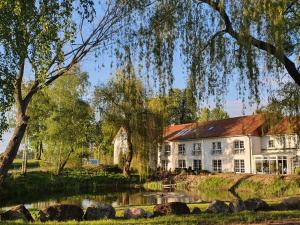 uma casa grande com um lago em frente em Van der Valk Golfhotel Serrahn - Adult Only em Serrahn