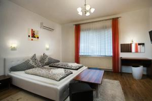 1 dormitorio con cama, mesa y ventana en Bathory Apartments, en Hajdúszoboszló