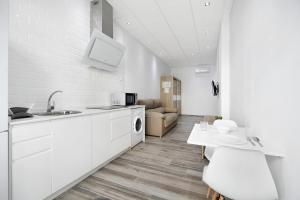 biała kuchnia ze zlewem i stołem w obiekcie Apartamento Venus 1 w mieście Conil de la Frontera