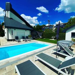 uma piscina com duas espreguiçadeiras e um guarda-sol em Lacus Pelso Holiday Home em Balatonfüred