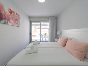 1 dormitorio blanco con 1 cama grande con almohadas rosas en Amarre Joy, en Puerto de Mogán